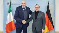 Guido Crosetto und Boris Pistorius schütteln sich freundlich die Hände für eine Fotoaufnahme.