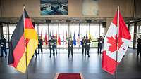 Die kanadische und deutsche Fahne stehen nebeneinander in einem Foyer.