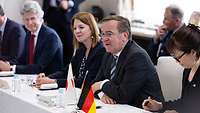 Verteidigungsminister Boris Pistorius zwischen zwei Frauen am Tisch sitzend 