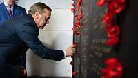 Minister Pistorius befestigt eine rote Blüte am Australian War Memorial. 