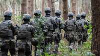 Soldaten marschieren in voller Ausrüstung durch einen Wald
