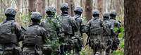 Soldaten marschieren in voller Ausrüstung durch einen Wald
