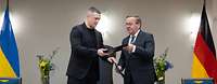 Minister Pistorius und sein ukrainischer Amtskollege tauschen schwarze Dokumentenmappe aus.