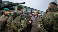 Boris Pistorius spricht mit Soldaten. Hinter ihm steht ein Panzer.