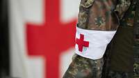 Ein Soldat trägt eine Armbinde mit dem roten Kreuz.