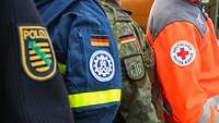 Ärmelabzeichen von Polizei, THW, Bundeswehr und Deutschem Roten Kreuz nebeneinander.