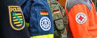 Ärmelabzeichen von Polizei, THW, Bundeswehr und Deutschem Roten Kreuz nebeneinander.