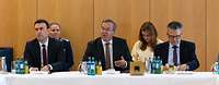 Schmid, Pistorius und Kiesewetter sitzen an einem Tisch während einer Veranstaltung.
