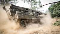 Ein Bergepanzer "Büffel" fährt durch eine staubige Schneise in einem Wald.