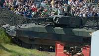 Ein Panzer im Vordergrund und viele Personen im Hintergrund.