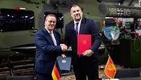 Minister Pistorius gibt seinem montenegrinischen Amtskollegen die Hand, beide halten unterzeichnete Dokumente