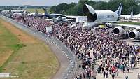 Viele Menschen und stehende Flugzeugen auf einem Gelände
