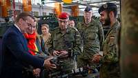 Boris Pistorius und mehrere Soldaten schauen sich eine Drohne an.