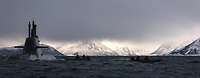 Ein aufgetauchtes U-Boot setzt Soldaten ab. Im Hintergrund sind schneebedeckte Berge zu sehen.