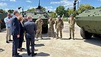 Soldaten und zivile Personen stehen vor mehreren Panzern