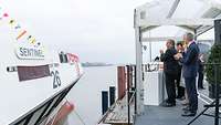 Mehrere Personen stehen klatschend vor einem Schiff.