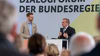 Verteidigungsminister Pistorius und eine weitere Person stehen auf einer Bühne.