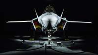 Ein beleuchtetes Kampfflugzeug vom Typ F-35A steht in einer dunklen Halle.