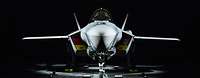 Ein beleuchtetes Kampfflugzeug vom Typ F-35A steht in einer dunklen Halle.