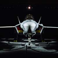 Ein beleuchtetes Kampfflugzeug vom Typ F-35A steht in einer dunklen Halle.