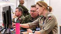 Ein deutscher Soldat und eine dännische Soldatin schauen zusammen auf einen Computerbildschirm