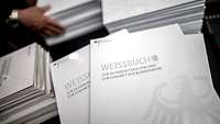 Mehrere Stapel Weißbücher liegen nebeneinander.