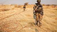 Deutsche Soldaten mit Metalldetektoren in steppenartiger Landschaft